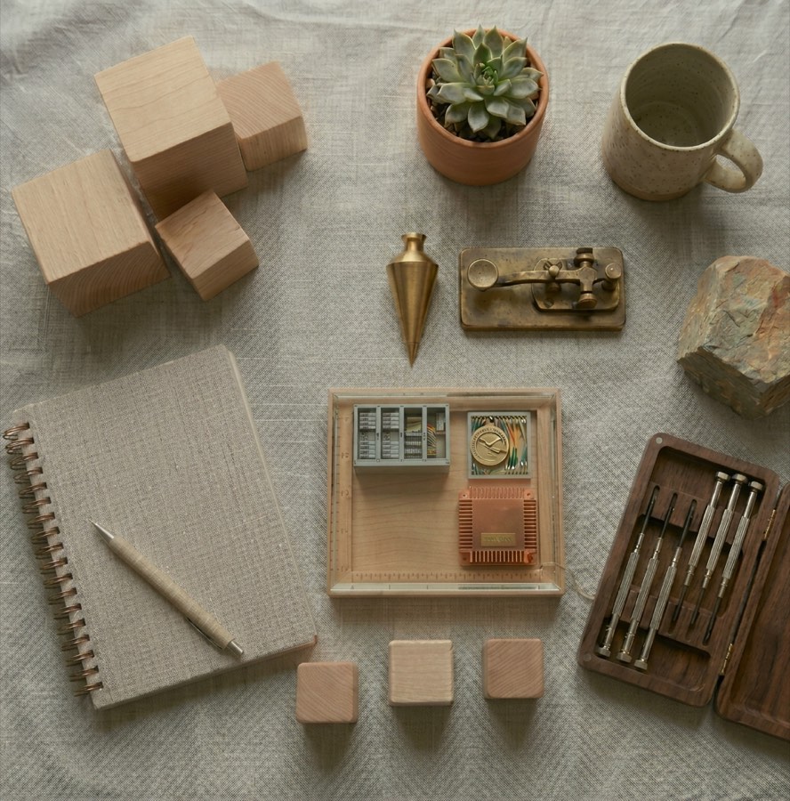 A flat-lay of wooden blocks, precision tools, and a notebook on linen